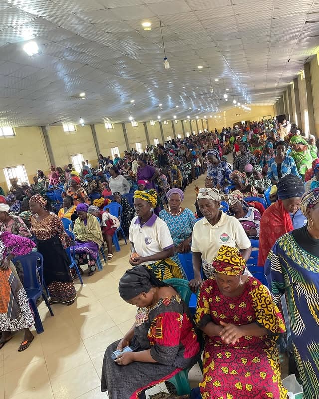 A large seated crowd of women in colorful traditional dress